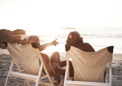 Mature couple sitting on beach chairs looking at ocean